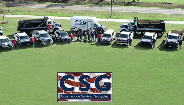 The Construction Services Group team standing with CSG’s branded trucks and work vehicles