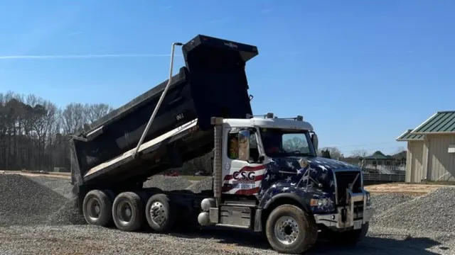 CSG dump truck unloading gravel at a job site